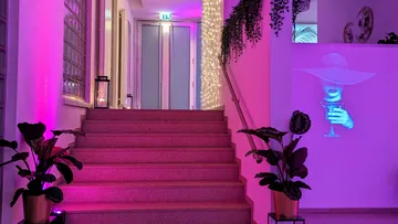 Staircase with pink lighting and projected drink.