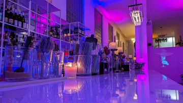Eine Bar mit bunten Lichtern, Gläsern und Flaschen.