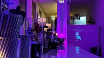 Moderne Bar mit leuchtenden Farben und einem projizierten Cocktail.