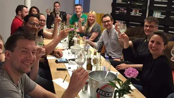 Gruppe von Menschen hebt Gläser in Feier-Atmosphäre.