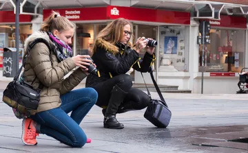 Zwei Frauen fotografieren auf einer Straße im Freien.