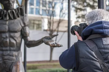 A photographer takes a picture of a statue.