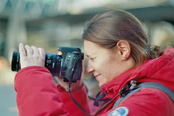 A woman takes pictures with a camera in an urban environment.