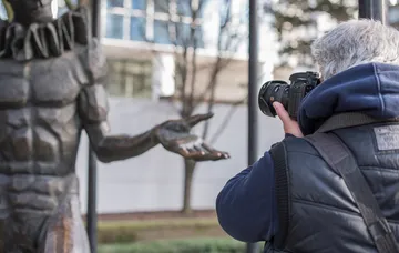Photographer takes a picture of an outdoor statue.