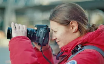 Eine Person fotografiert mit einer Kamera im Freien.