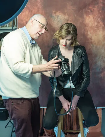 Fotograf zeigt einer Frau auf einer Kamera Bildbewertungen in Studio.