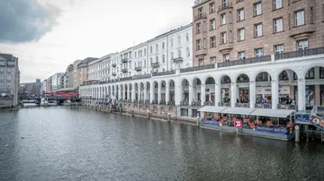 A picturesque waterfront with historic buildings, arcades and restaurants that stretch along a quiet canal.