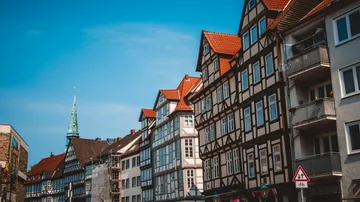 Historic half-timbered houses stand along a busy street.