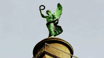 A statue holds a wreath on a tall tower.