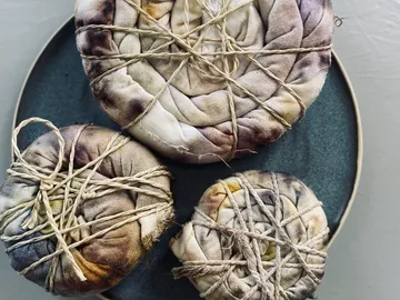 Three bundles of fabric folded in thread on a plate.