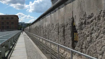 Mauer steht, Besucher gehen entlang auf einem Bürgersteig.