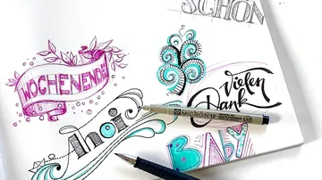 Sketchbook shows colorful lettering and drawings.