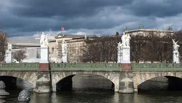 Brücke mit Statuen, umgeben von Wasser und Bauten.