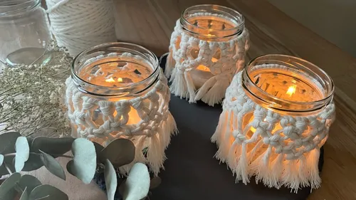 Three glass candle holders light up on a table.