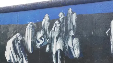 Graffiti shows wrapped figures against a blue background.