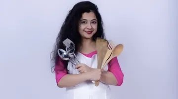 Woman with cooking utensils hugging in light background.
