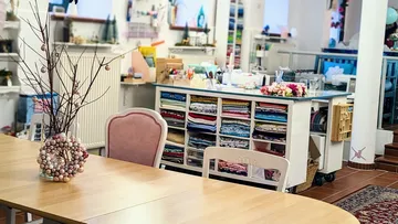 Wooden table with decoration surrounded by sewing material in a studio.