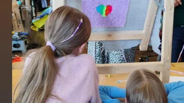 Zwei Mädchen betrachten ein farbiges Herzbild auf einer Leinwand.