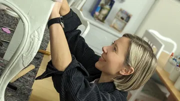Woman repairing furniture in a bright, creative room.
