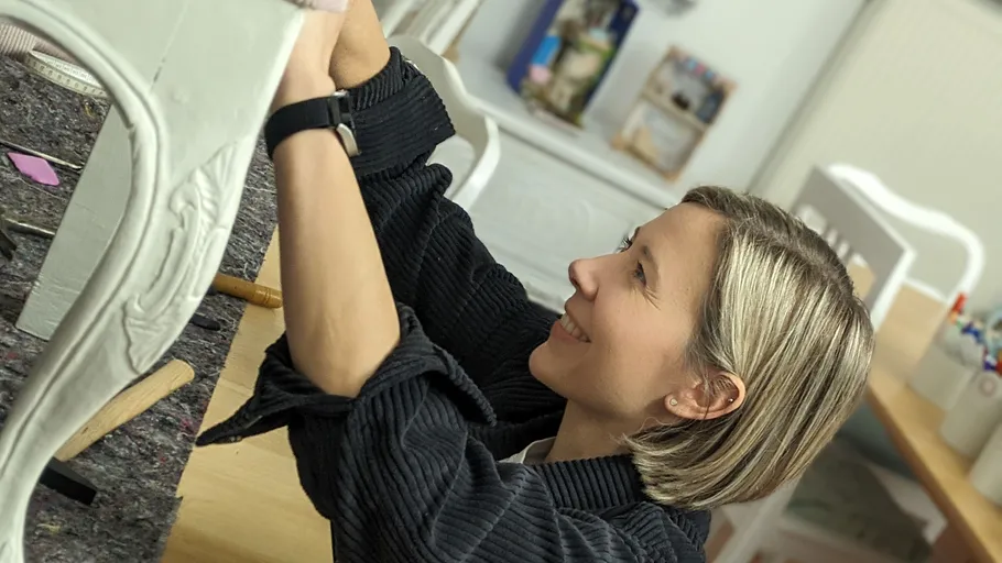 Woman repairing furniture in a bright, creative room.