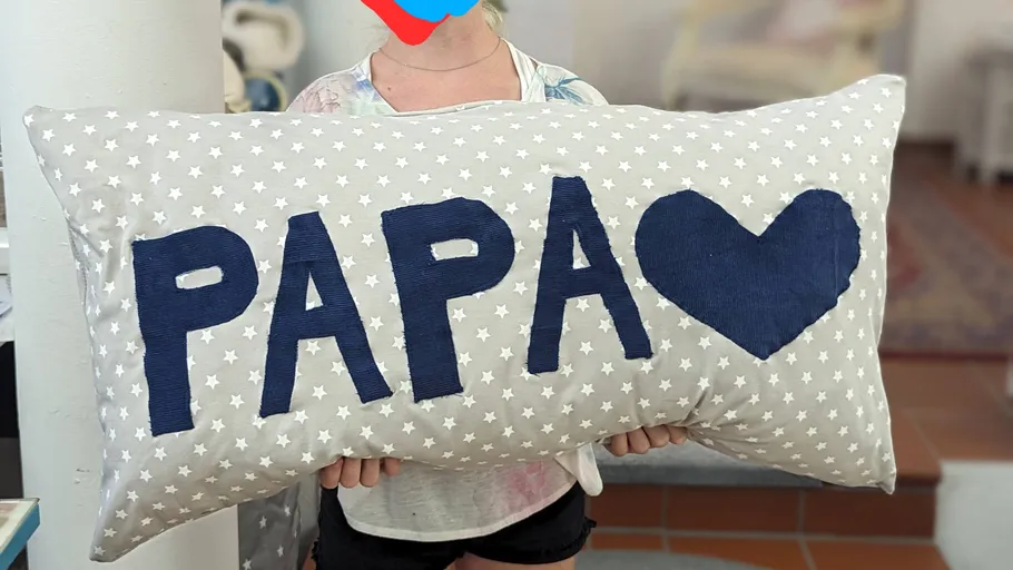 Kissen mit der Aufschrift `PAPA` und Herz, gehalten von jemandem.