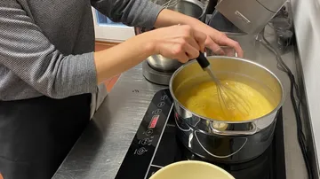 A person is stirring in a pot on a stove.