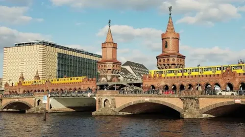 Zug fährt über die Brücke neben historischen Türmen am Wasser.