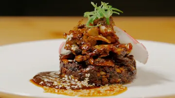 Beautifully prepared dish with meat and sauce on a plate.
