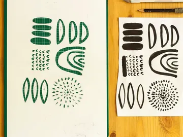 Green pattern paper and black shapes on a wooden background.