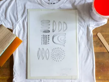 White t-shirt lies under template with various patterns.