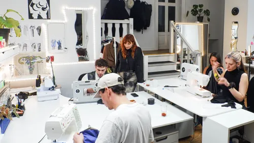 Nähmaschinen arbeiten, während Teilnehmer in einem Atelier kreieren.