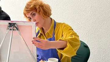 A person concentrates on painting on a canvas.