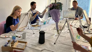People paint on easels in a bright room.