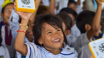 A girl raises a solar light with a smile.