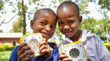Two kids are holding solar lights and smiling happily.