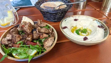 Gegrilltes Fleischsalat und Hummus auf einem Tisch serviert.