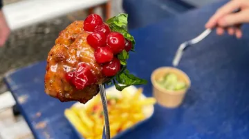 Fleischbällchen auf Gabel mit Preiselbeeren, Salat, Pommes frites.