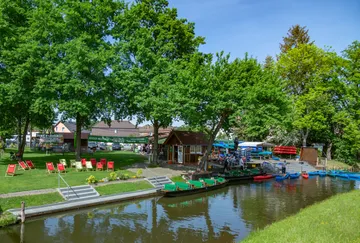 Benches stand by the calm water, people enjoy nature.