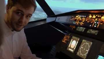 Man sits in the cockpit and steers an airplane.