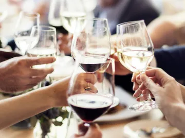 Glasses are raised while people celebrate together.