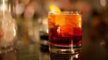 Ein Glas Cocktail steht auf der Theke, leuchtet orange.