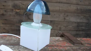 Eine Lampe steht auf einem weißen Sockel, umgeben von Holz.