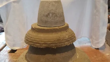 Pottery of various sizes is placed one above the other on a table.