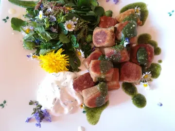 Pflanzliche Speisen mit grüner Sauce auf einem weißen Teller.