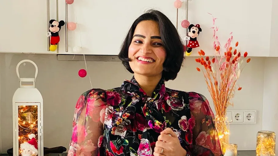 Woman smiling in a decorated kitchen with flowers.