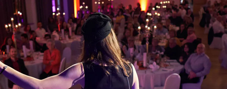 Woman speaking in front of an audience at a festive event.