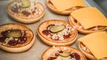 Rolls with ketchup, onions, pickles and cheese are topped.