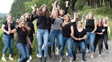 Eine Gruppe Frauen springt fröhlich in der Natur.