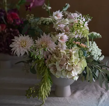 Blumenarrangement in grau-weißer Vase auf dem Tisch.