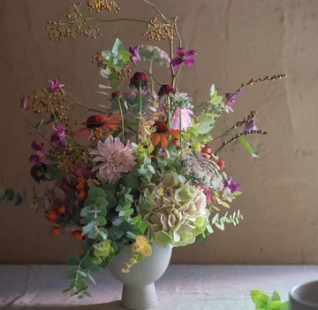 Colourful flowers in a vase are on a table.